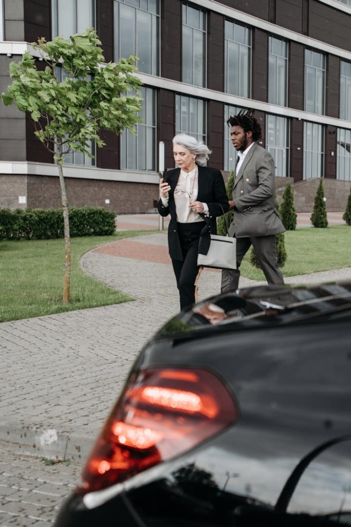 Two business professionals walking on a pathway, using a mobile phone.